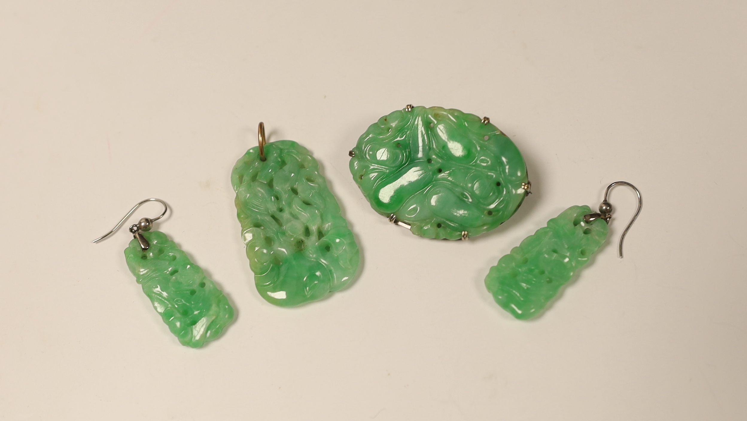 Four items of white metal mounted carved jade jewellery, comprising a brooch, 37mm, a pendant and pair of earrings.